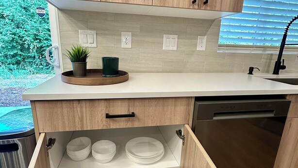 Una cocina moderna con armarios de madera, lavavajillas integrado y una encimera con una planta en maceta.