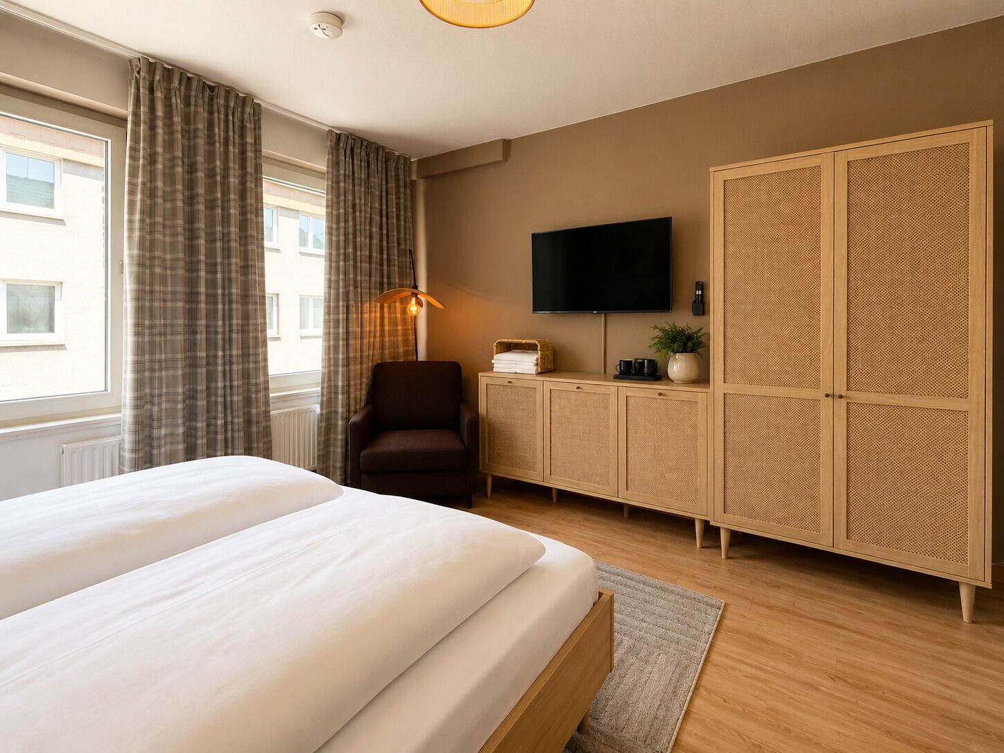 A hotel room with a bed, a TV, a wardrobe, and a chair.