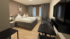 A modern hotel room with a bed, a desk, a chair, a TV, and a painting on the wall. - SHIN CENTRAL (Essen)