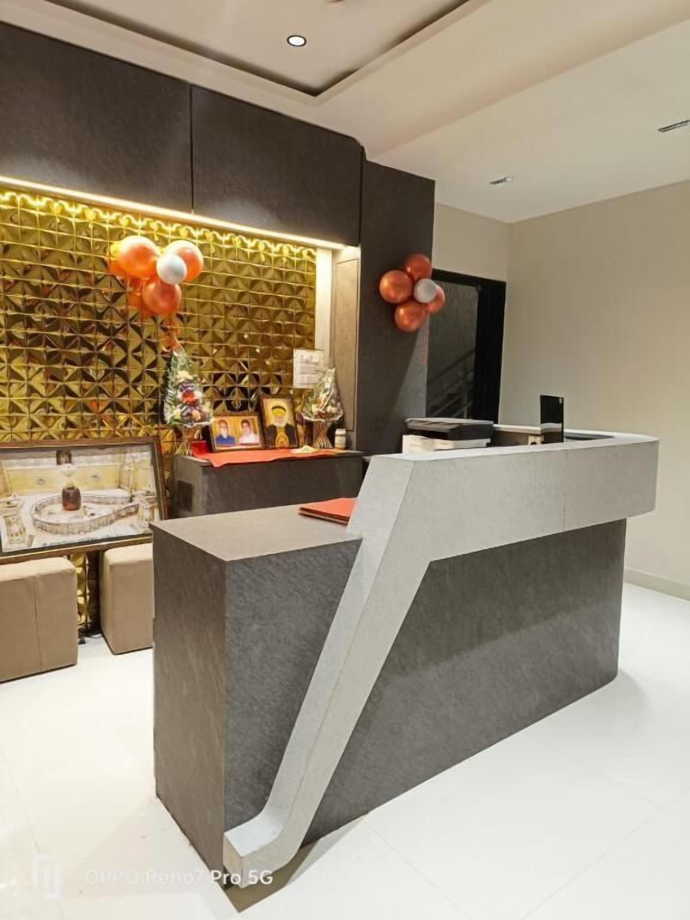 A modern reception desk with a curved design, a patterned wall behind it, and a framed picture on the left.