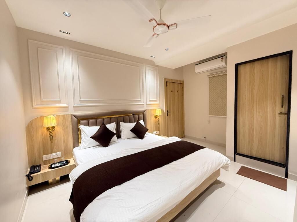 A hotel room with a large bed, bedside lamps, a ceiling fan, and a wooden door.
