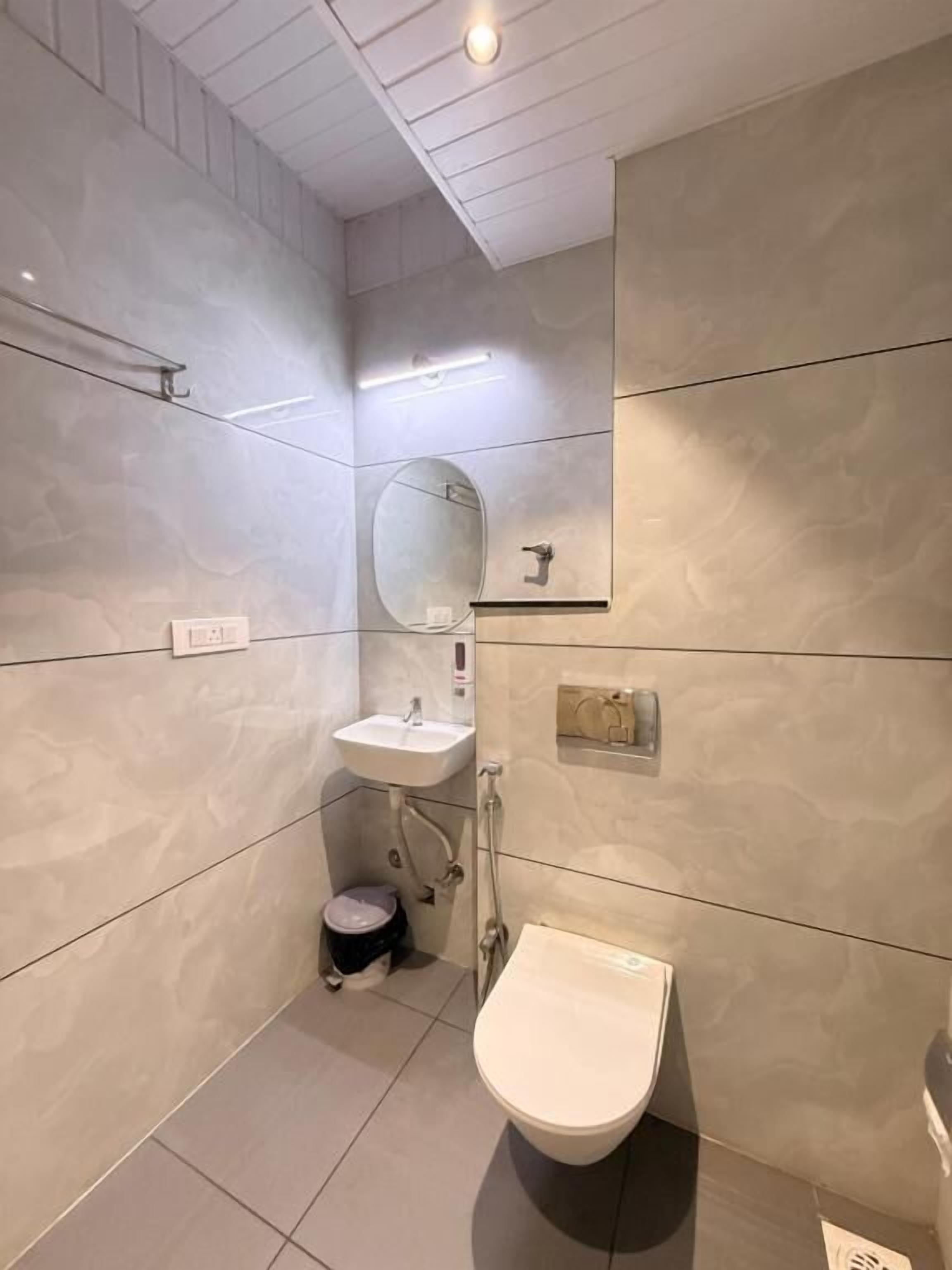 A modern bathroom with a pedestal sink, a mirror, a toilet, and a bidet.