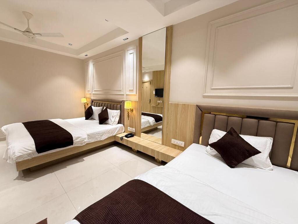 A hotel room with two beds, a ceiling fan, a large mirror, and a TV.