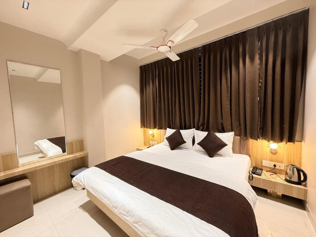 A hotel room with a large bed, a ceiling fan, a nightstand with a lamp, and a mirror.
