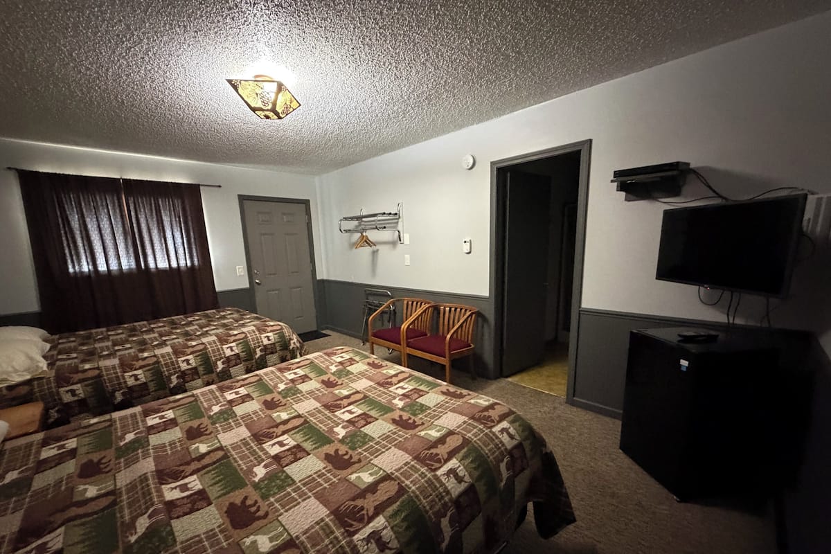 Una habitación de hotel con dos camas, un televisor, un escritorio y una silla.