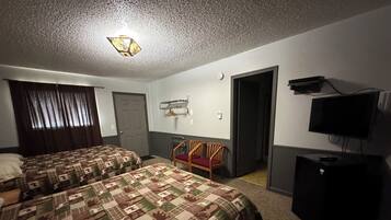 A hotel room with two beds, a TV, a desk, and a chair.