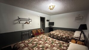 Habitación de hotel con dos camas, un escritorio, una silla, un televisor y una lámpara colgante.