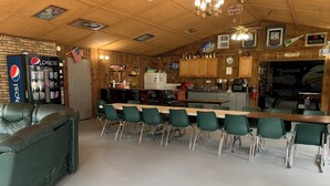 Un restaurante con zona de bar, sillas verdes, una barra y un refrigerador de Pepsi.