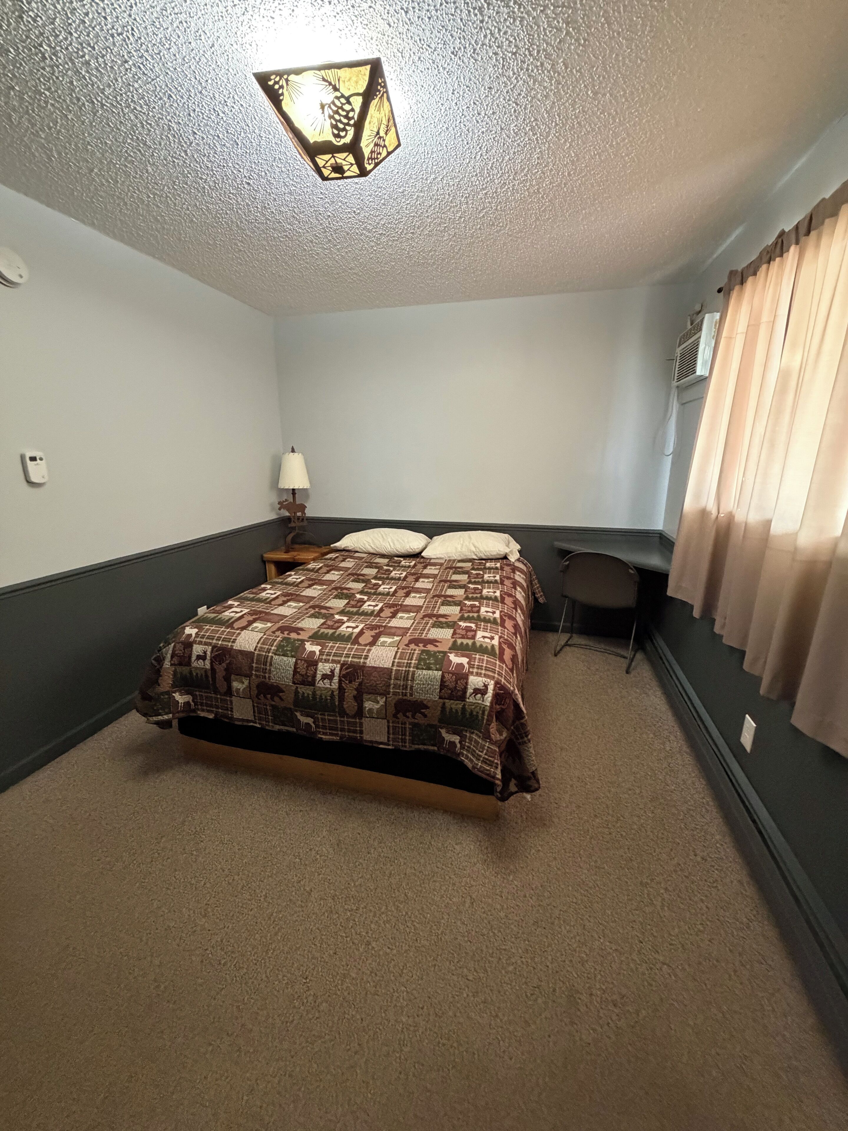 A bedroom with a bed, a desk, and a chair.