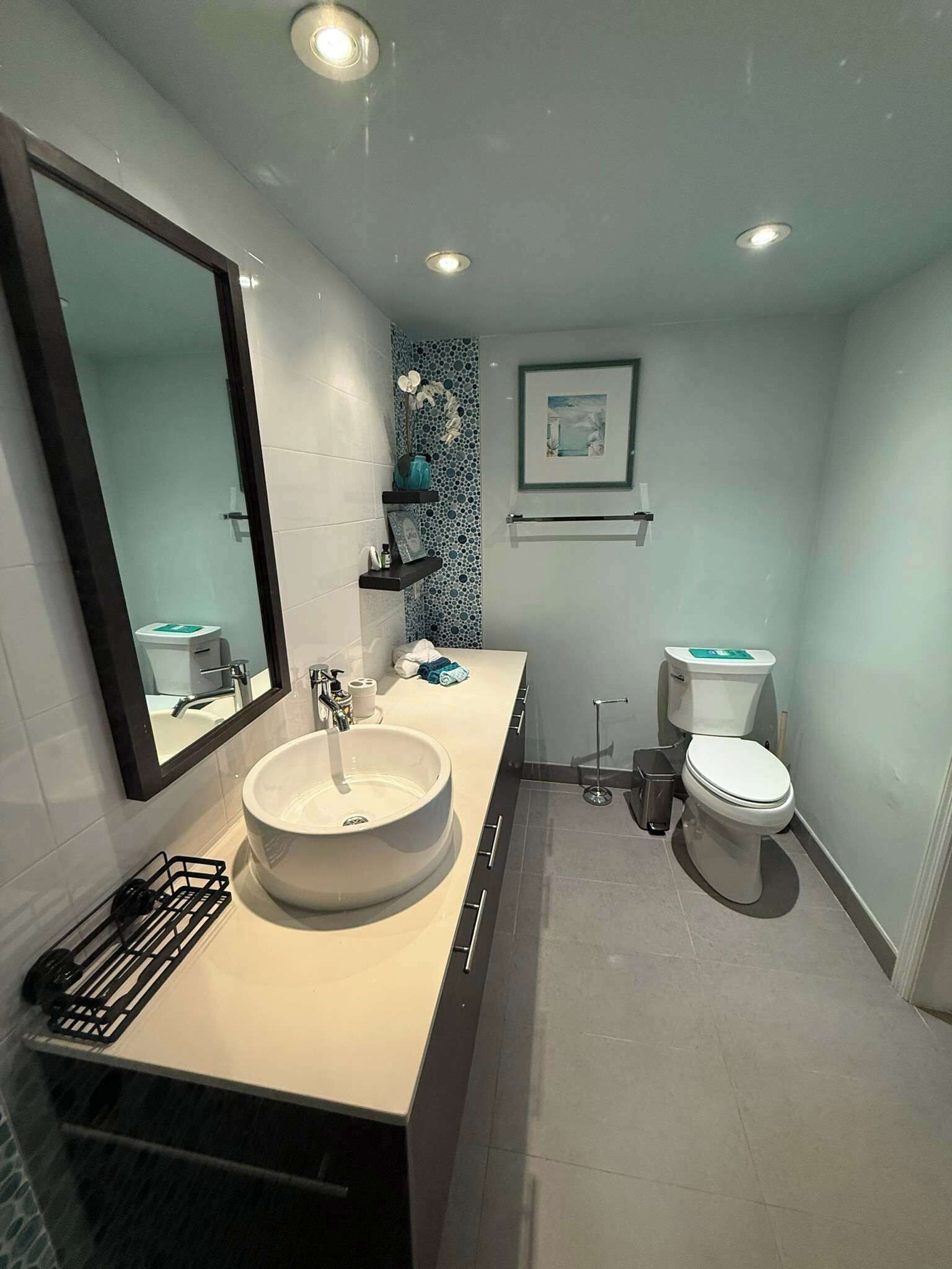A modern bathroom with a large sink, toilet, and a mirror.