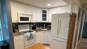 Una cucina moderna con mobili bianchi, un forno a microonde, un fornello e un frigorifero.