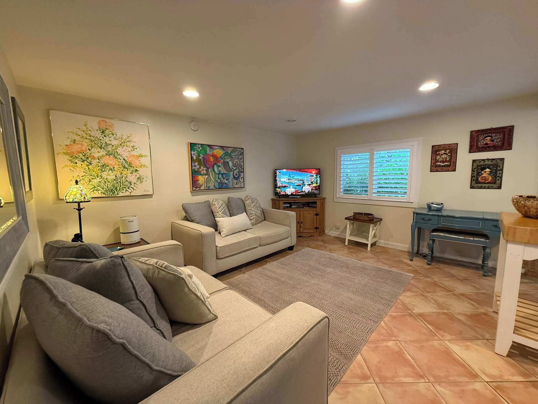 A living room with a beige sofa, a television, and artwork on the walls.