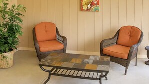 Two wicker chairs with orange cushions, a woven table, and a potted plant. - Romantic Nest-Enjoyable 1-bedroom bungalow in charming Colorado Springs (Colorado Springs)