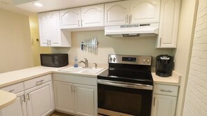 A kitchen with white cabinets, a black stove, a microwave, and a coffee maker. - Romantic Nest-Enjoyable 1-bedroom bungalow in charming Colorado Springs (Colorado Springs)