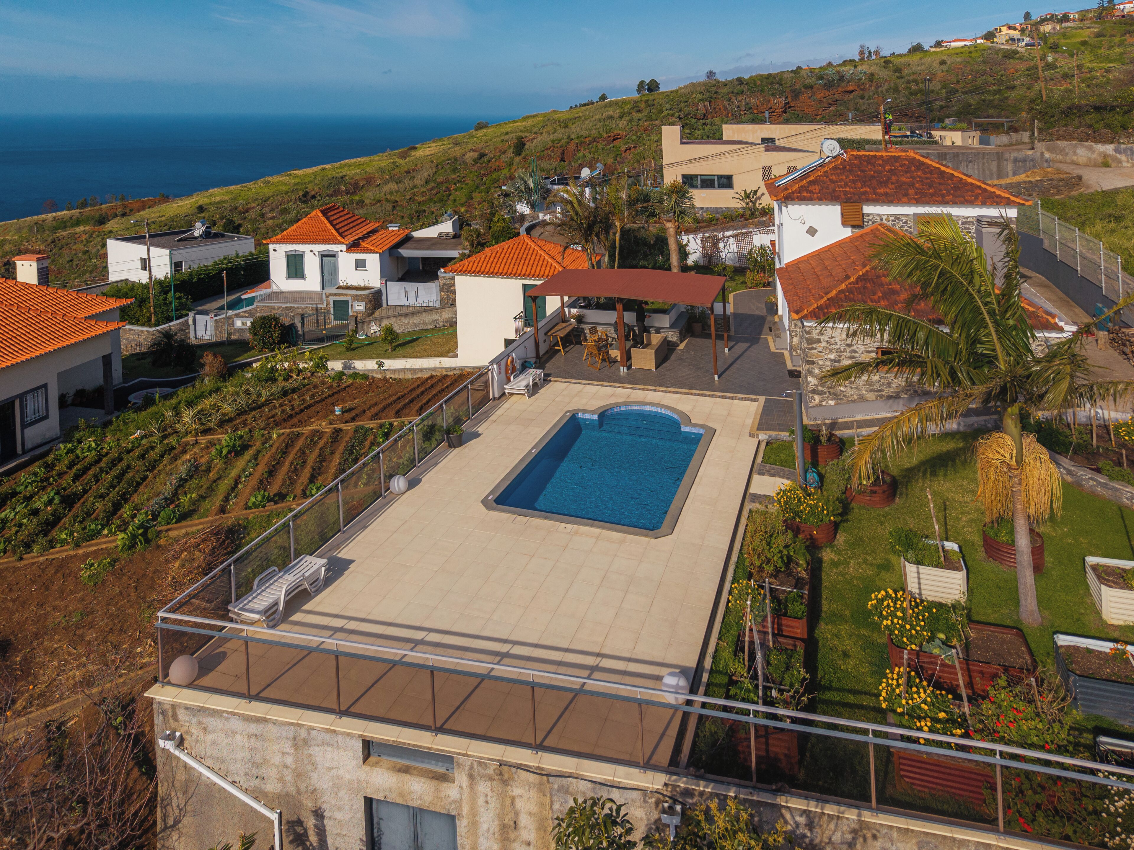 Un quartier résidentiel doté d’une piscine, de maisons aux toits recouverts de tuiles rouges et offrant une vue sur la mer.
