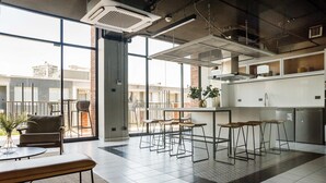 Una cocina moderna con taburetes de bar, una mesa de comedor y ventanas amplias con vistas a la ciudad.