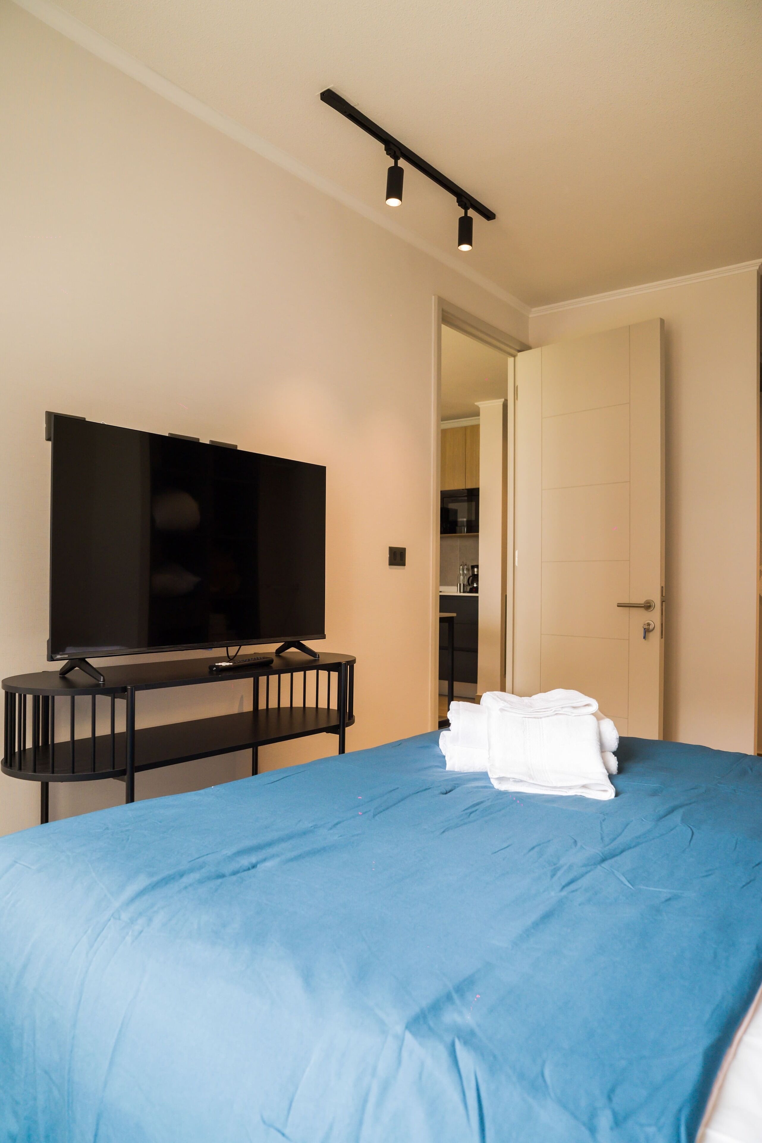 Une chambre d’hôtel équipée d’un lit, d’un téléviseur à écran plat, d’un bureau et d’une porte donnant sur une cuisine.