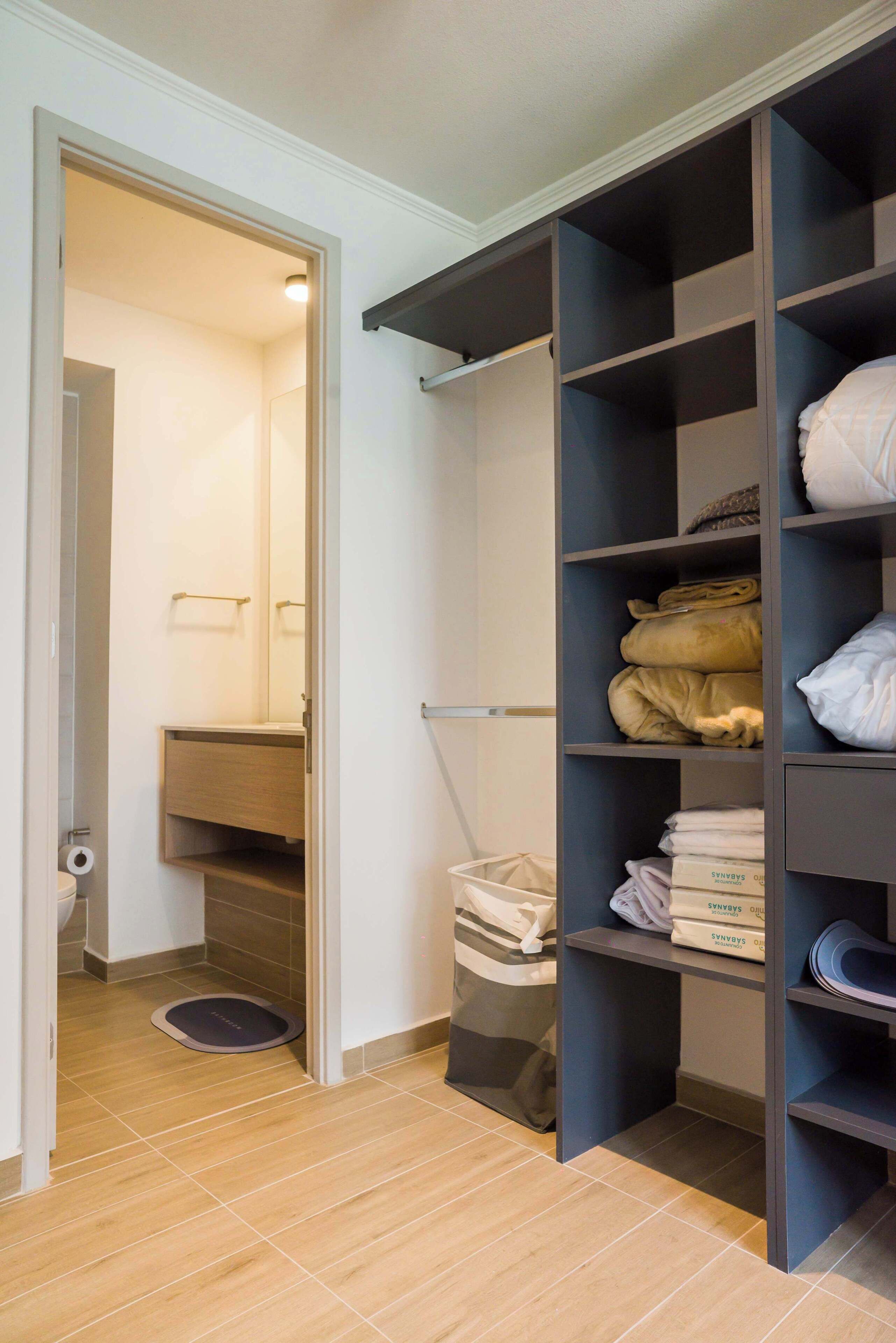 Un dressing avec des étagères, une tringle et un bac de rangement.