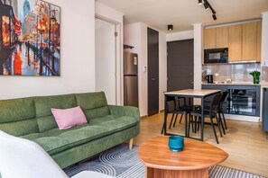 Ein stilvolles Wohnzimmer mit einem grünen Sofa, einem Couchtisch und einem Stadtbild.