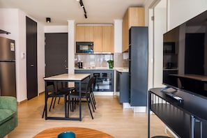 A modern kitchen with a dining area, a flat-screen TV, and a built-in oven. - Bright 2BR Apartment in Providencia | Ideal For 5 (Providencia)