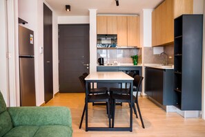 A modern kitchen with a dining table and chairs, a built-in oven, and a coffee machine. - Bright 2BR Apartment in Providencia | Ideal For 5 (Providencia)