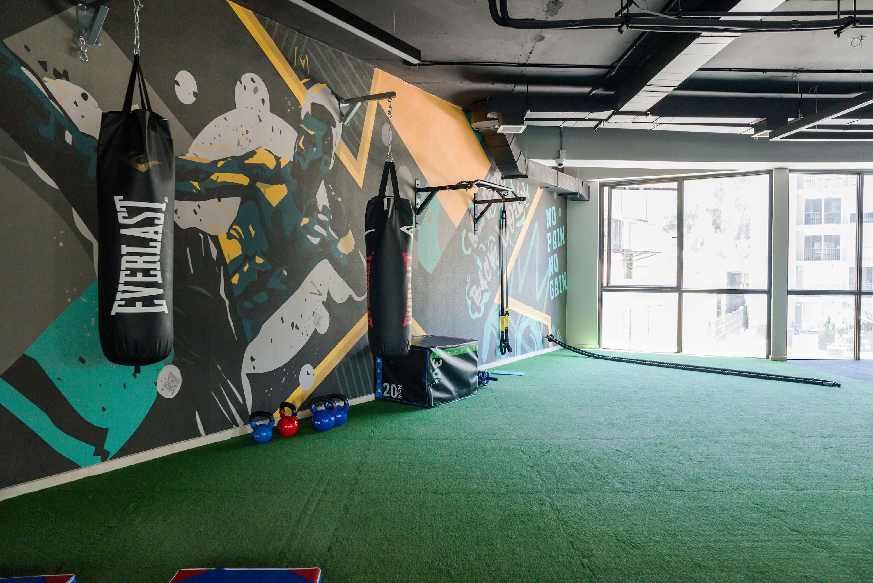 Ein Fitnessraum mit einem Schlagbeutel, Kettlebells und einer Wand mit motivierenden Kunstwerken.