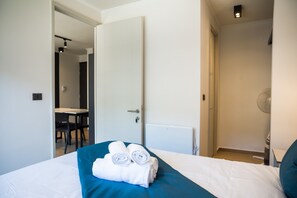 Una habitación de hotel con una cama, una mesa y una silla al fondo.
