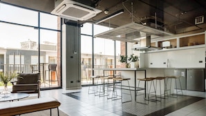 Une cuisine moderne avec des tabourets de bar, une table à manger et de grandes fenêtres donnant sur la ville.