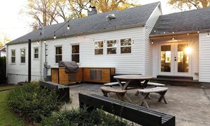Una casa blanca con un patio que tiene una mesa de madera y bancos.