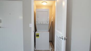 A laundry room with a front-loading washer and dryer, a door with a handle, and a light fixture above the appliances.
