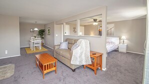 A living room with a sofa, coffee table, and a dining area with a table and chairs.
