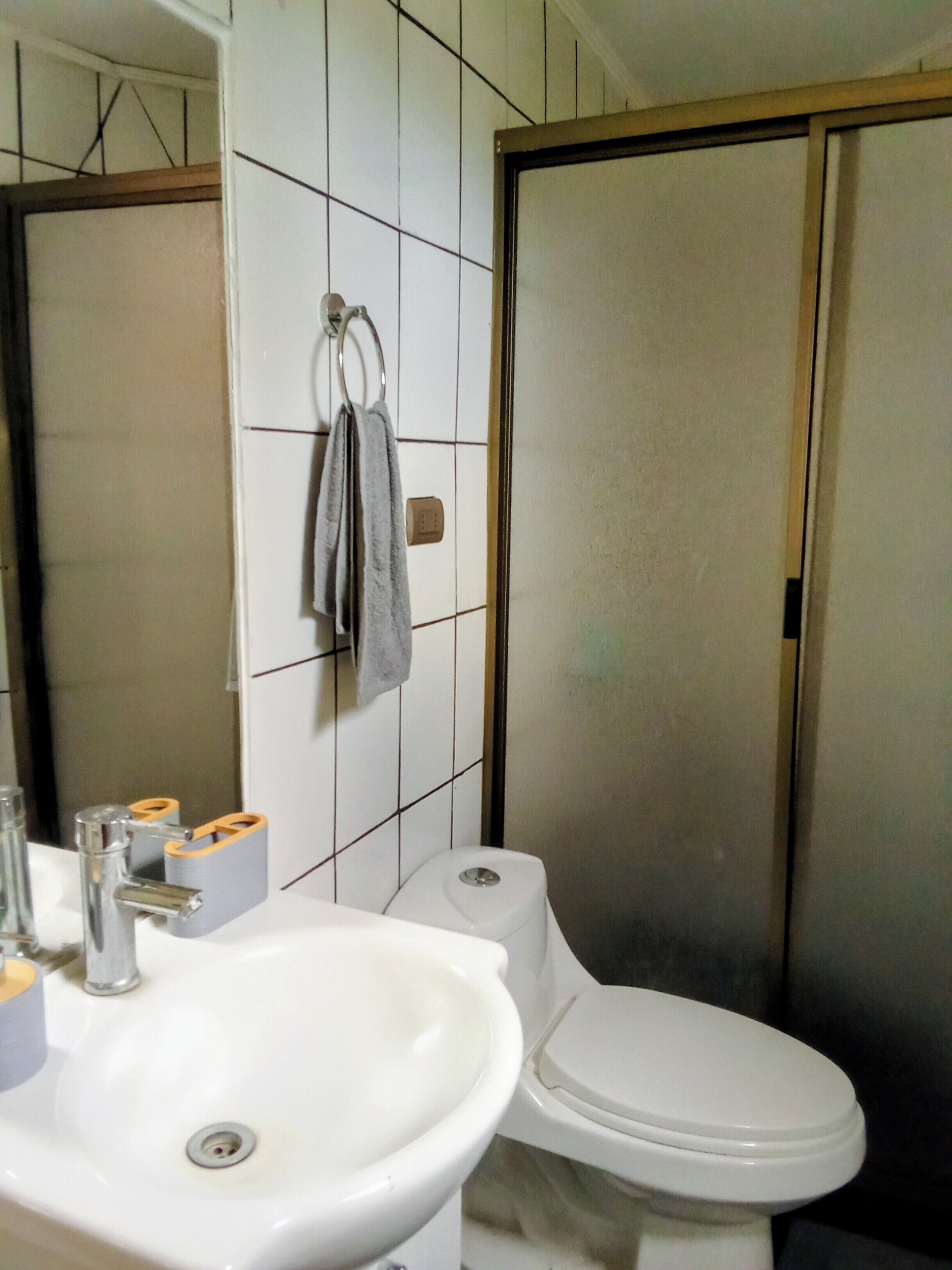 A bathroom with a white sink, toilet, and a towel hanging on a rack.