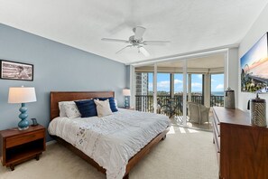 A bedroom with a large bed, a ceiling fan, a nightstand, a dresser, and a balcony with a view of the ocean. - Gorgeous Ocean Views, Pool, Amenities Galore, Condo Living at it Finest! (Fort Myers Beach)
