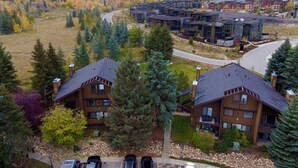 A residential area with modern multi-story buildings, a winding road, and a backdrop of autumn-colored trees and mountains. - Red Pine Retreat at Canyons Village (Park City)