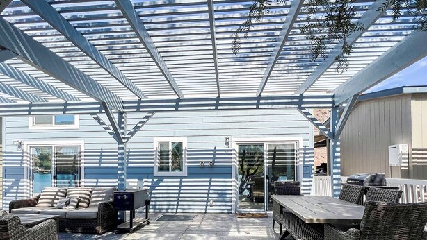 An outdoor patio area with wicker furniture, a wooden table, and a covered seating area. - All-american Escape, Riverfront! WB3 (Parker Dam)