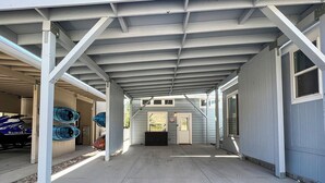 A covered parking area with a concrete floor, metal beams, and a row of doors leading to garages. - All-american Escape, Riverfront! WB3 (Parker Dam)