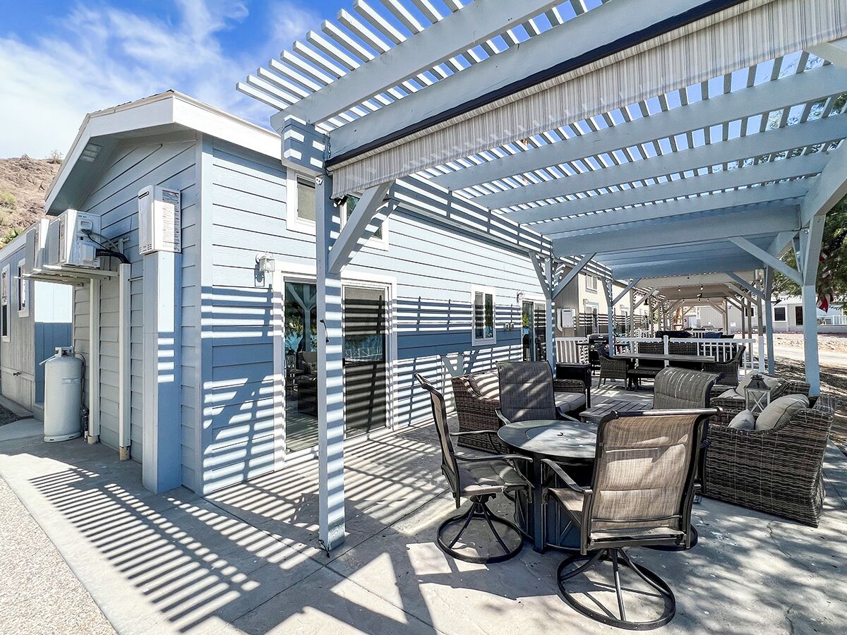 A covered outdoor patio with a dining table and chairs, a grill, and a water heater.