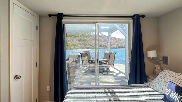 Ein Schlafzimmer mit einer großen Glasschiebetür, die auf einen Balkon mit Tisch und Stühlen führt.