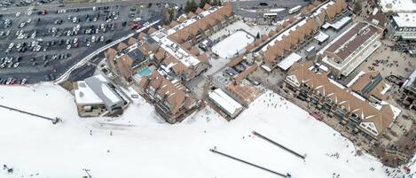 An aerial view of a commercial area with parking lots, buildings, and a snowy landscape.