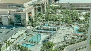 Un hôtel doté de plusieurs piscines, de palmiers et d’un parking.