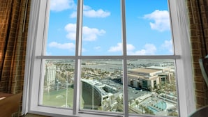 Une grande fenêtre offrant une vue dégagée sur le paysage urbain, avec notamment un grand immeuble et un parking.