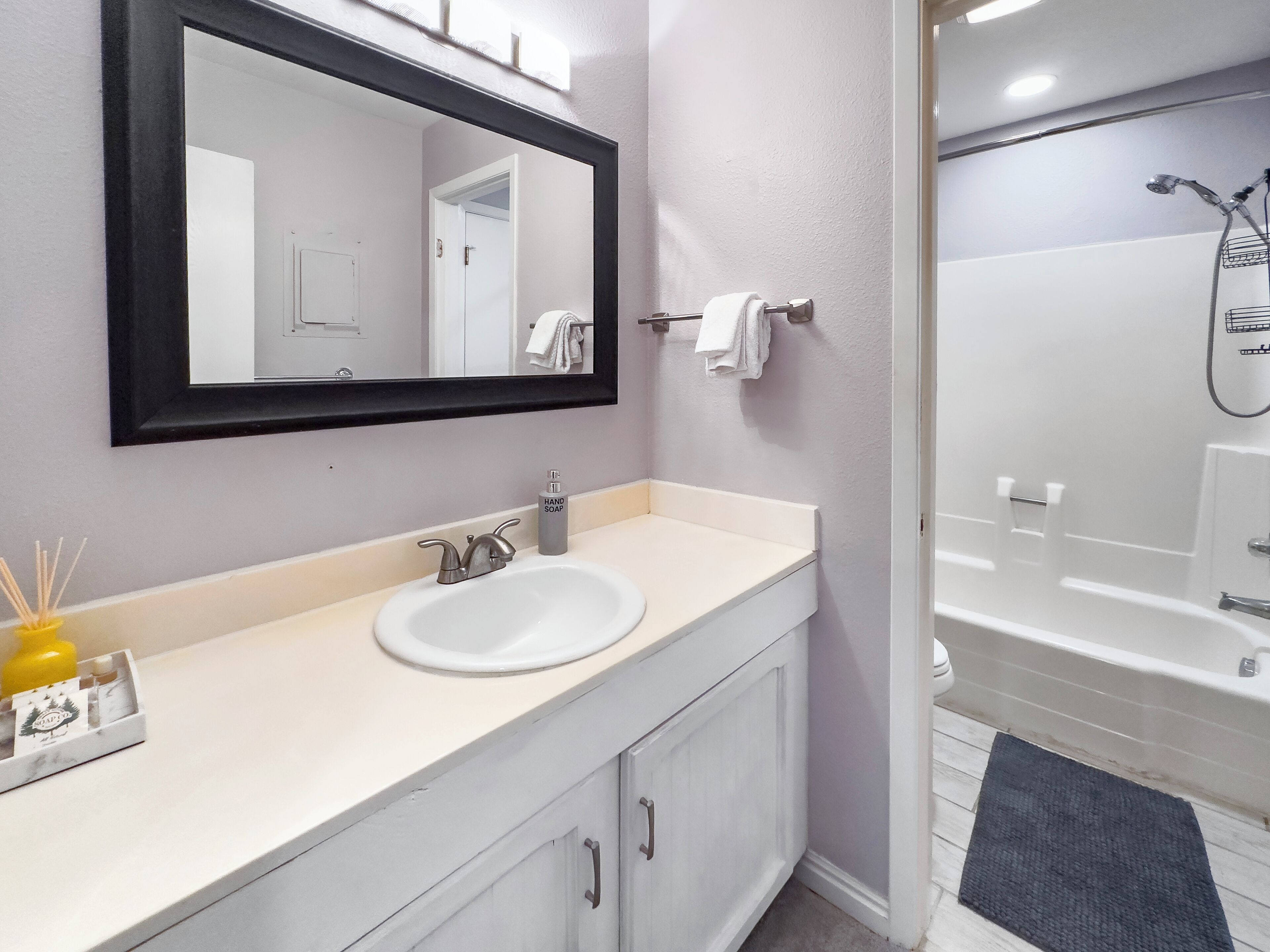 A bathroom with a white sink, a mirror, and a shower.