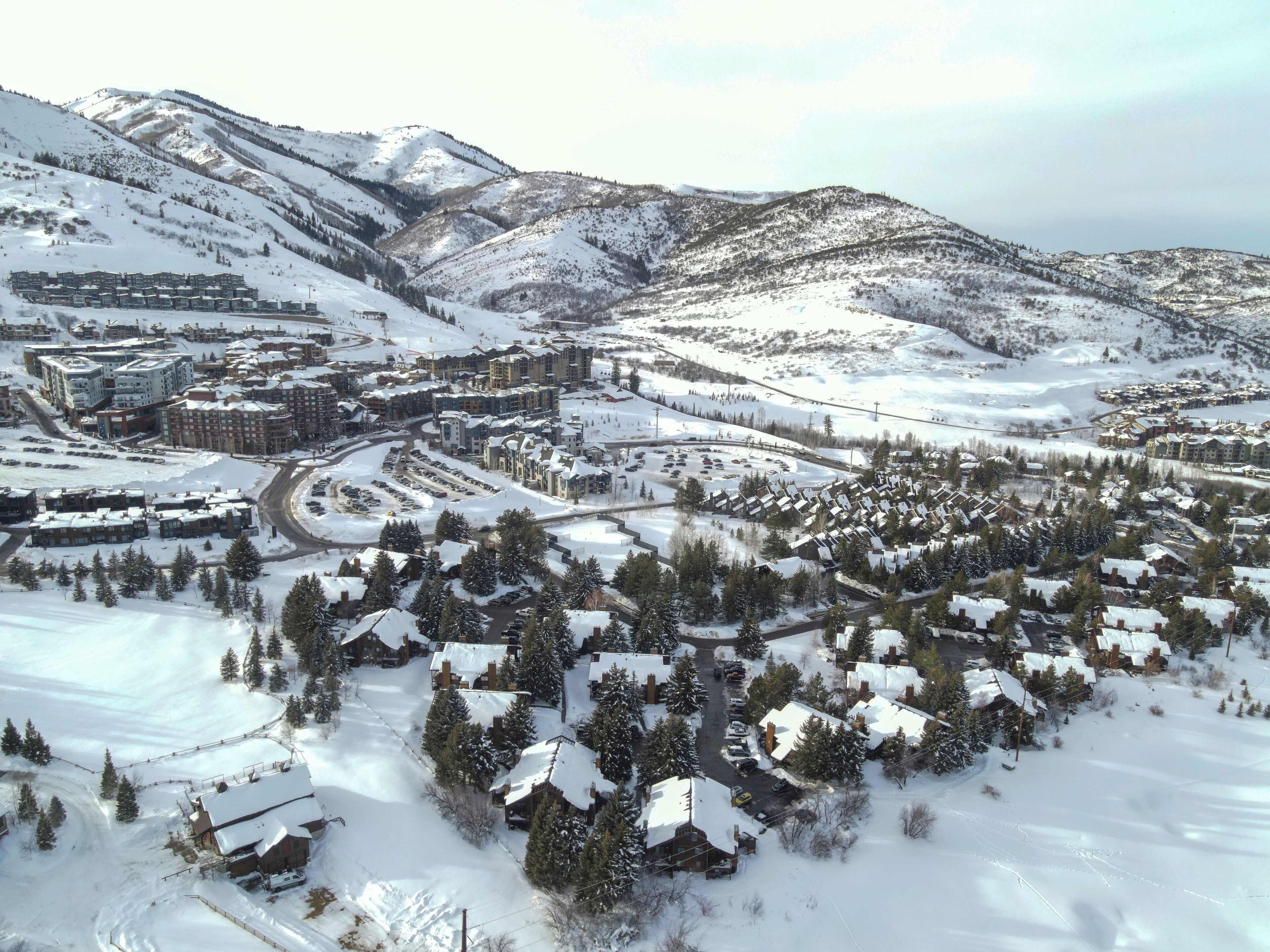 Un pueblo cubierto de nieve en la montaña, con varios edificios, incluyendo un hotel grande con patio central y varias construcciones más pequeñas.