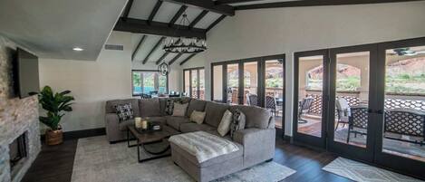 A spacious living room with a sectional sofa, a fireplace, and a large sliding glass door leading to an outdoor patio.