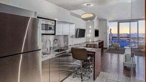 A modern kitchen with stainless steel appliances, a dining area with a bar, and a large window offering a city view. - Incredible Views 51st Floor High-rise Studio -balcony (Las Vegas)