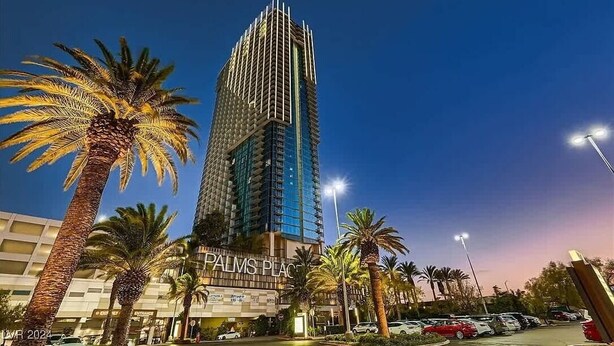 A tall, modern building with a sign reading "PALMS PLACE" at the base, surrounded by palm trees and a parking lot. - Incredible Views 51st Floor High-rise Studio -balcony (Las Vegas)