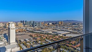 A cityscape with a prominent 'PALMS' building, various commercial buildings, and a clear blue sky. - Incredible Views 51st Floor High-rise Studio -balcony (Las Vegas)