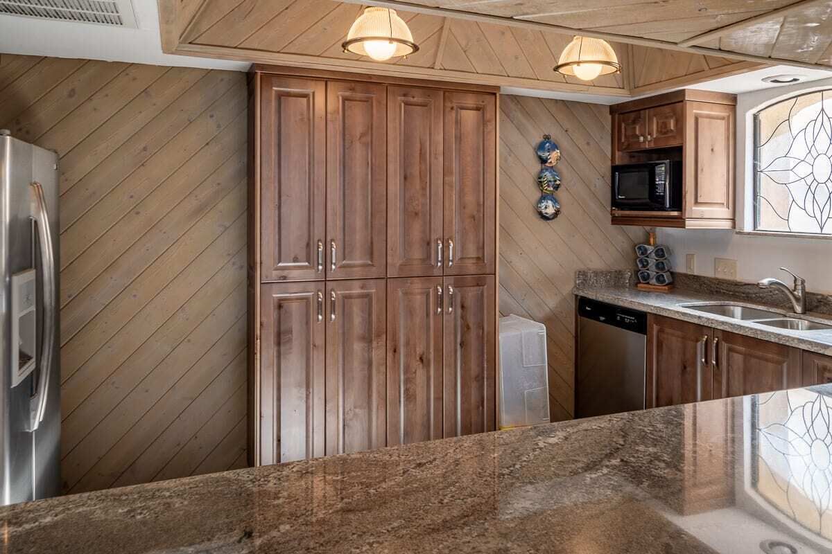 A kitchen with wooden cabinets, a stainless steel refrigerator, a microwave, and a dishwasher.