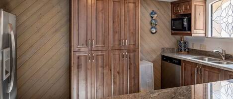 A kitchen with wooden cabinets, a stainless steel refrigerator, a microwave, and a dishwasher.