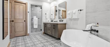 Une salle de bain moderne avec une baignoire sur pieds, un meuble-lavabo à deux vasques et un grand miroir.